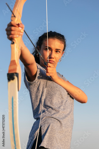 Archeress aiming with bow and arrow photo