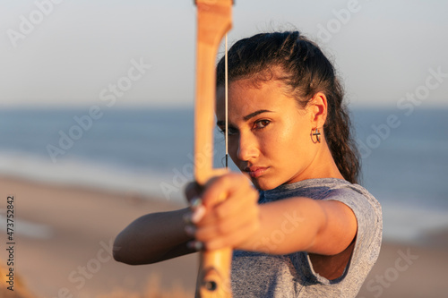 Serious woman practicing archery at beach photo