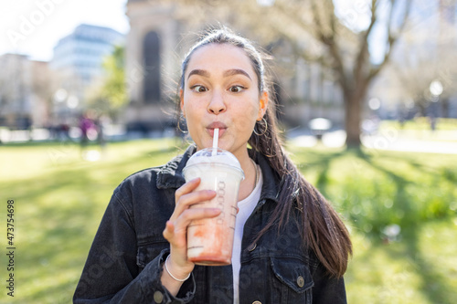 Young woman looking cross eyed while drinking milkshake at park