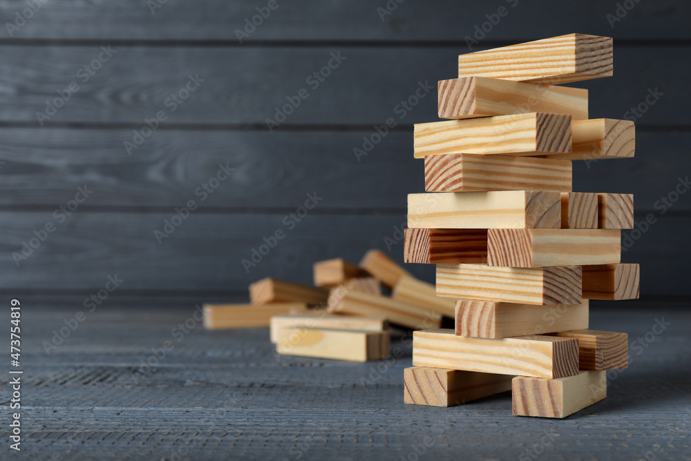Jenga tower made of wooden blocks on grey table, space for text Jenga tower made of wooden blocks on grey table, space for text