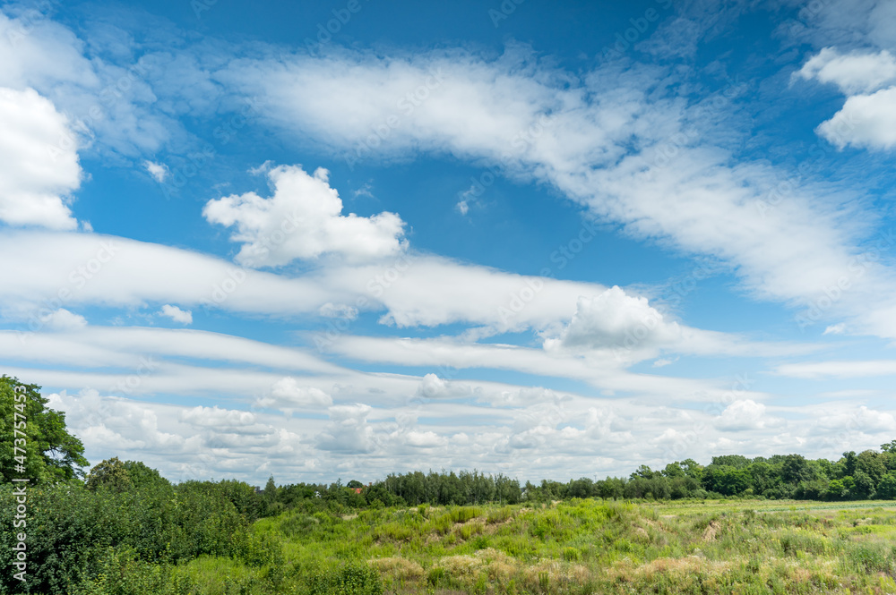 White fluffy clouds in blue sky background in green countryside at summer