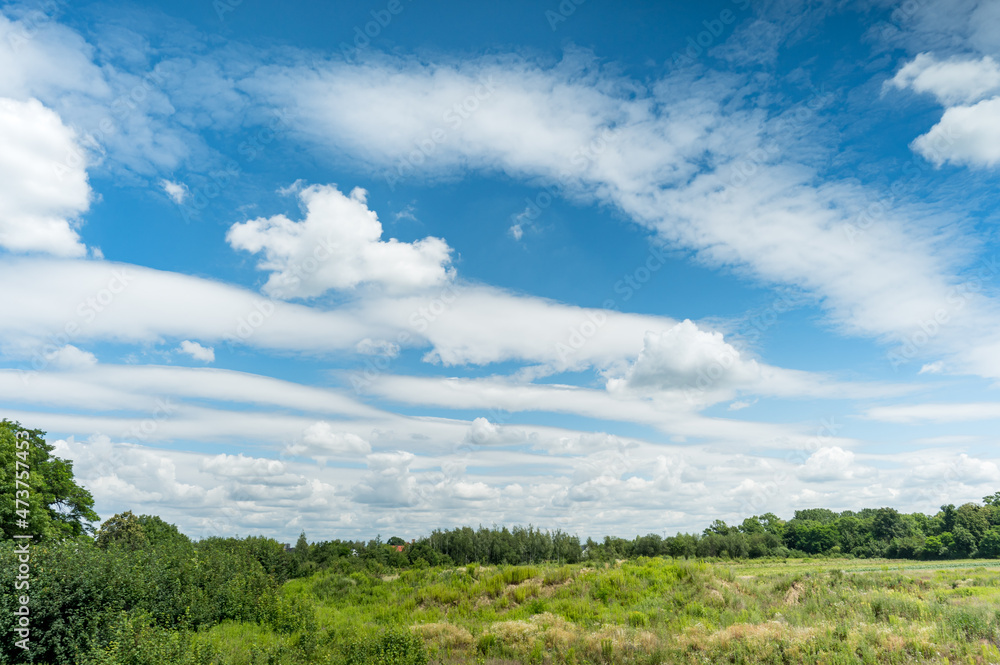 White fluffy clouds in blue sky background in green countryside at summer White fluffy clouds in blue sky background in green countryside at summer