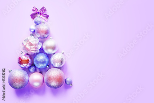 Innovative Christmas tree made of Christmas ornaments on purple background