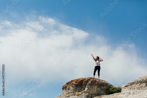 tourist woman traveler on top of a mountain alone looks at the landscape