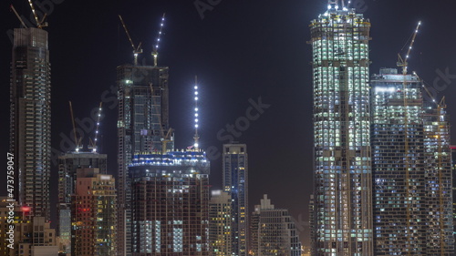 High multi-storey buildings under construction and cranes at night timelapse