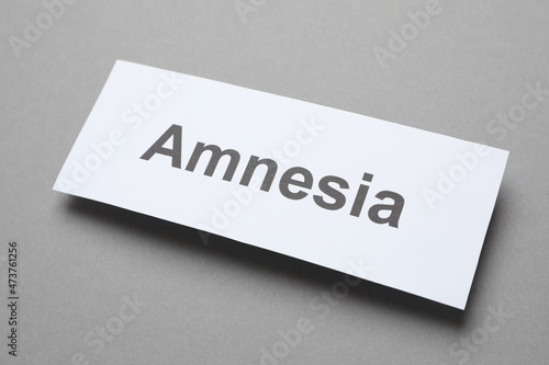 Card with word Amnesia on grey background, above view