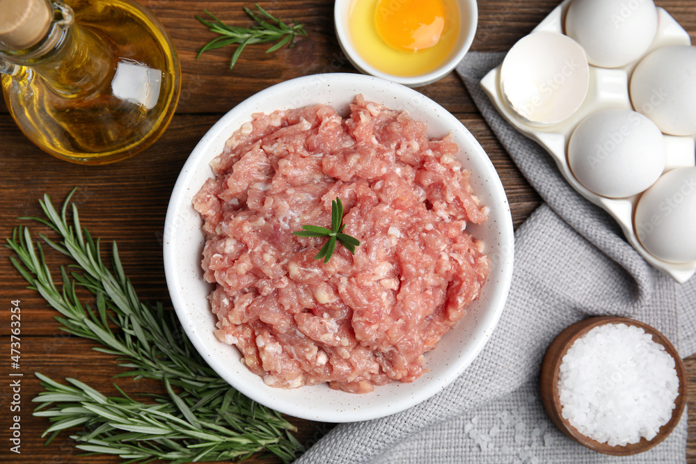 Raw chicken minced meat and ingredients on wooden table, flat lay Raw chicken minced meat and ingredients on wooden table, flat lay