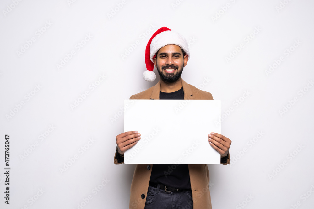 attractive man wearing santa christmas hat holding and pointing blank billboard or placard sign copy space for adding text advertising corporate or xmas whishes on white background attractive man wearing santa christmas hat holding and pointing blank billboard or placard sign copy space for adding text advertising corporate or xmas whishes on white background