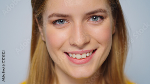 Closeup smiling attractive woman looking at camera on grey background.