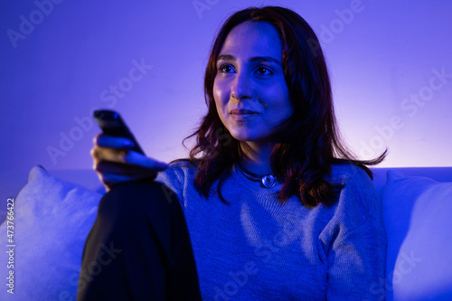 beautiful woman changing channels with remote, redhead young woman eating fruit while watching tv in her home