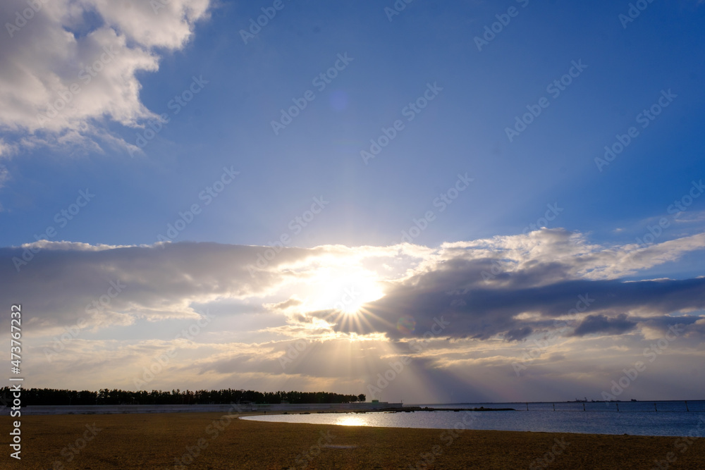 兵庫県芦屋市芦屋浜の夜明け。雲に覆われていて太陽が雲の間から顔を出し、天使の梯子が海に落ちる