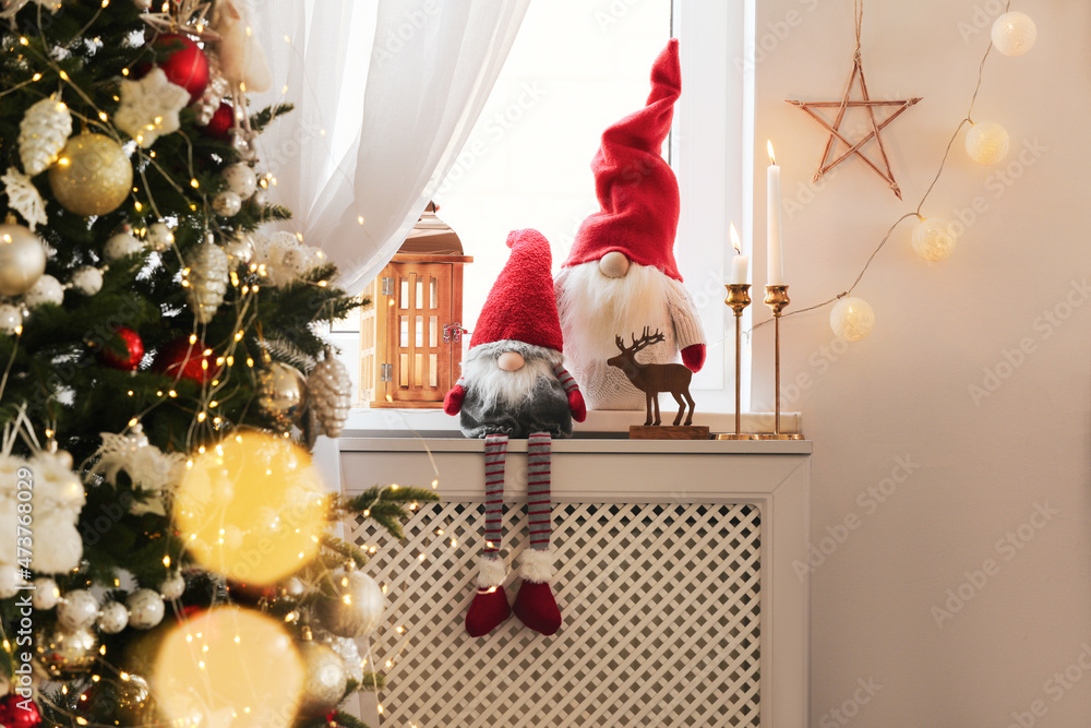 Obraz premium Cute gnomes near Christmas tree on windowsill in room