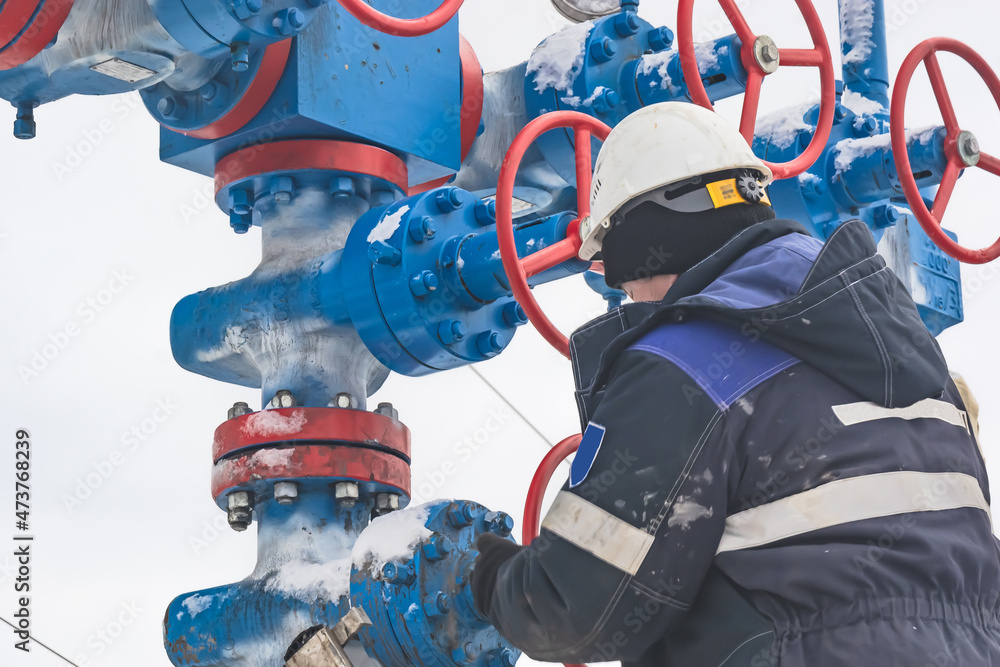 A gas company worker opens and closes high pressure valves on a gas tree A gas company worker opens and closes high pressure valves on a gas tree