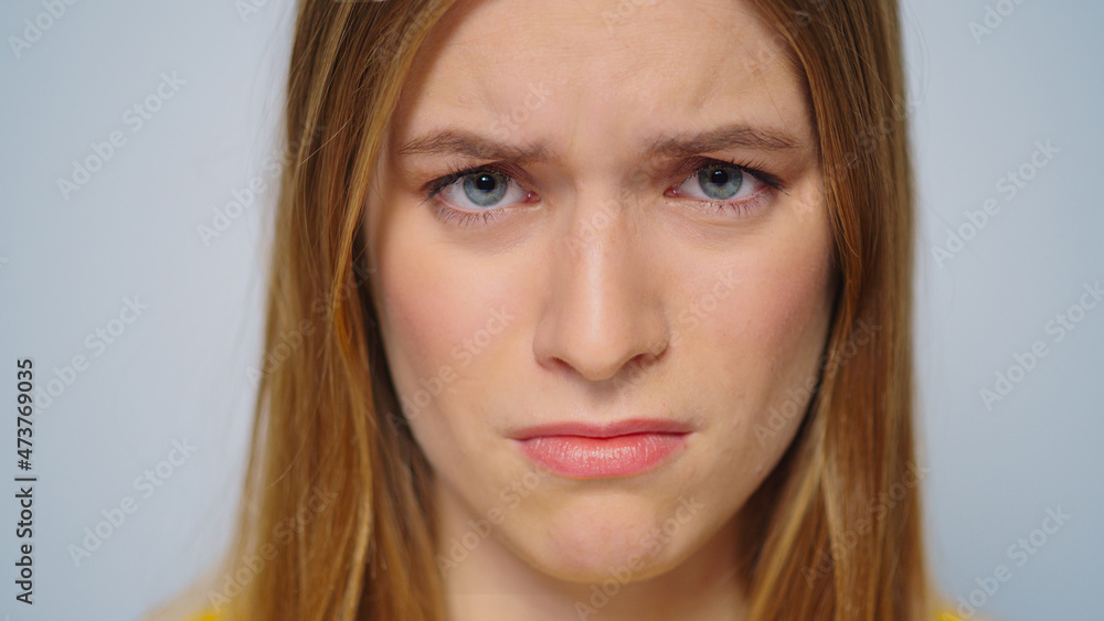 Closeup worried woman looking at camera on grey background in studio. Closeup worried woman looking at camera on grey background in studio.