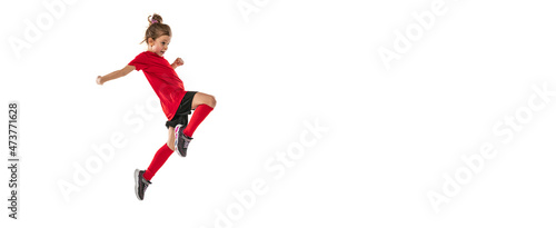 Full-length portrait of girl, child, football player in uniform training, kicking ball with knee isolated over white background. Flyer