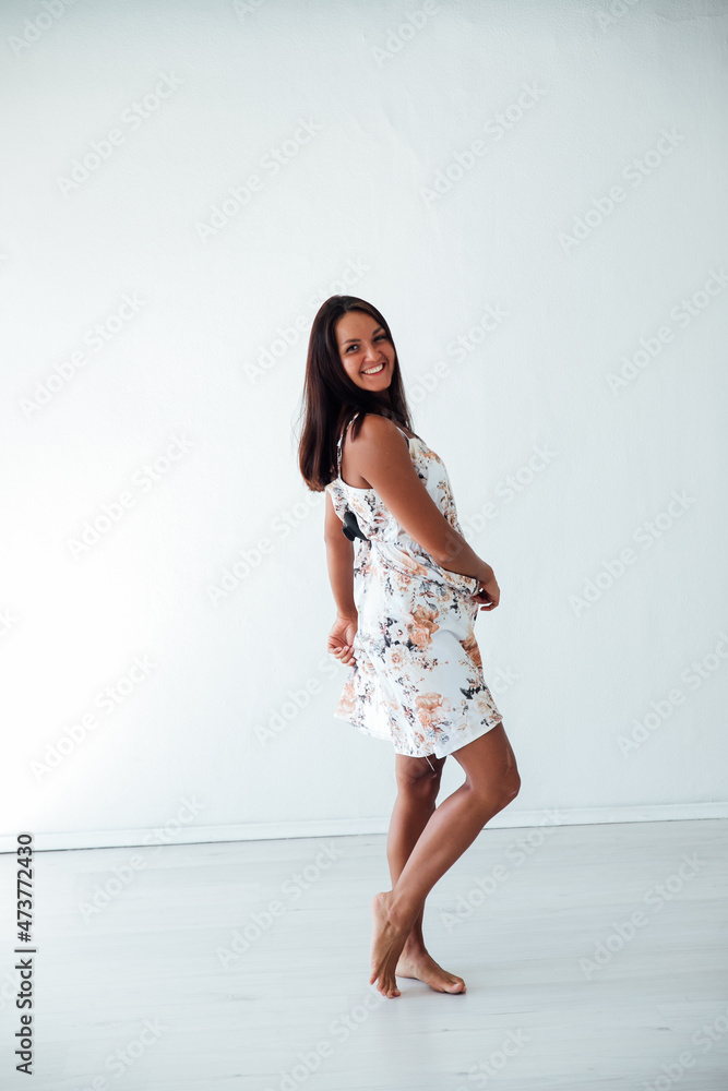 beautiful tanned woman in a summer dress with flowers in a white room beautiful tanned woman in a summer dress with flowers in a white room