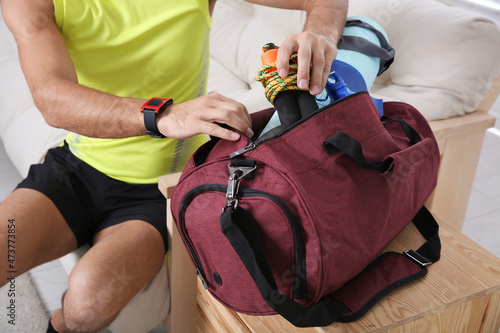 Man packing sports stuff for training into bag at home, closeup