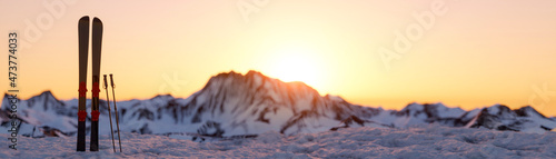 Fotografie, Obraz Skis and poles dug into the snow on a mountainside at sunrise 3d render panorami
