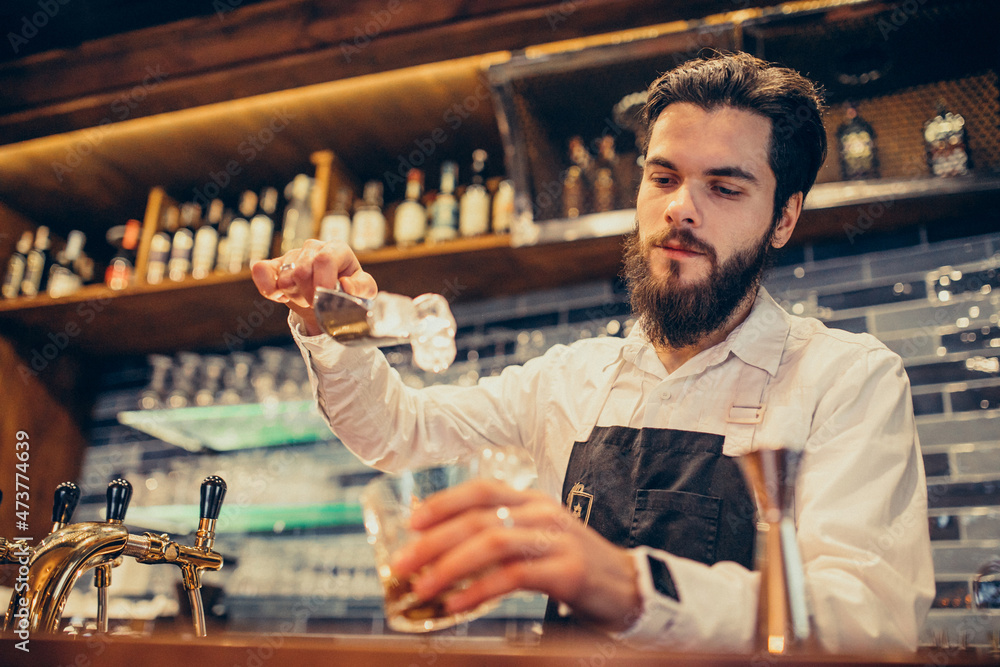 Handsome bartender making drinking and cocktails at a counter