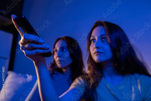 two female friends watching tv laughing at home, women watching tv with a remote at home at night laughing