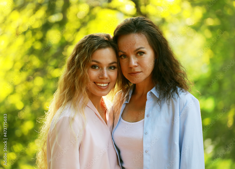 Mom and her adult daughter hold hands in a summer park Mom and her adult daughter hold hands in a summer park