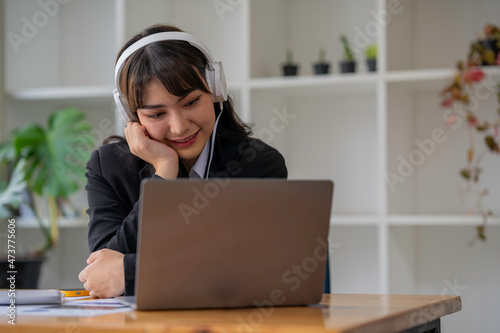 Portrait of a business woman happily wearing music headphones while working to relax after a hard day's work.