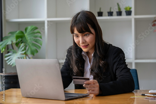 Businesswoman holding credit card while using laptop computer to buy or pay online, online shopping.