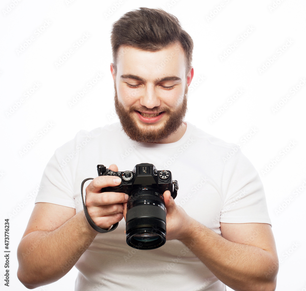 A young bearded male photographer is looking at the photos he has taken on his camera isolated on white background. A young bearded male photographer is looking at the photos he has taken on his camera isolated on white background.