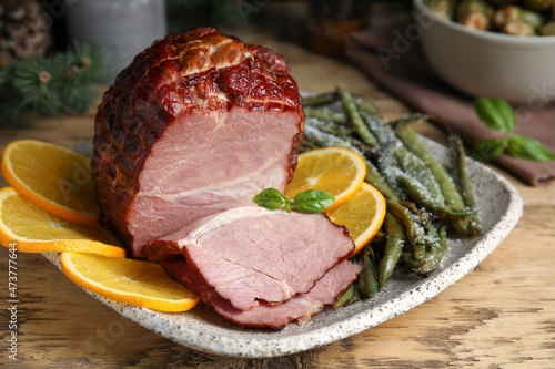 Delicious ham served with green beans and orange on wooden table, closeup. Christmas dinner