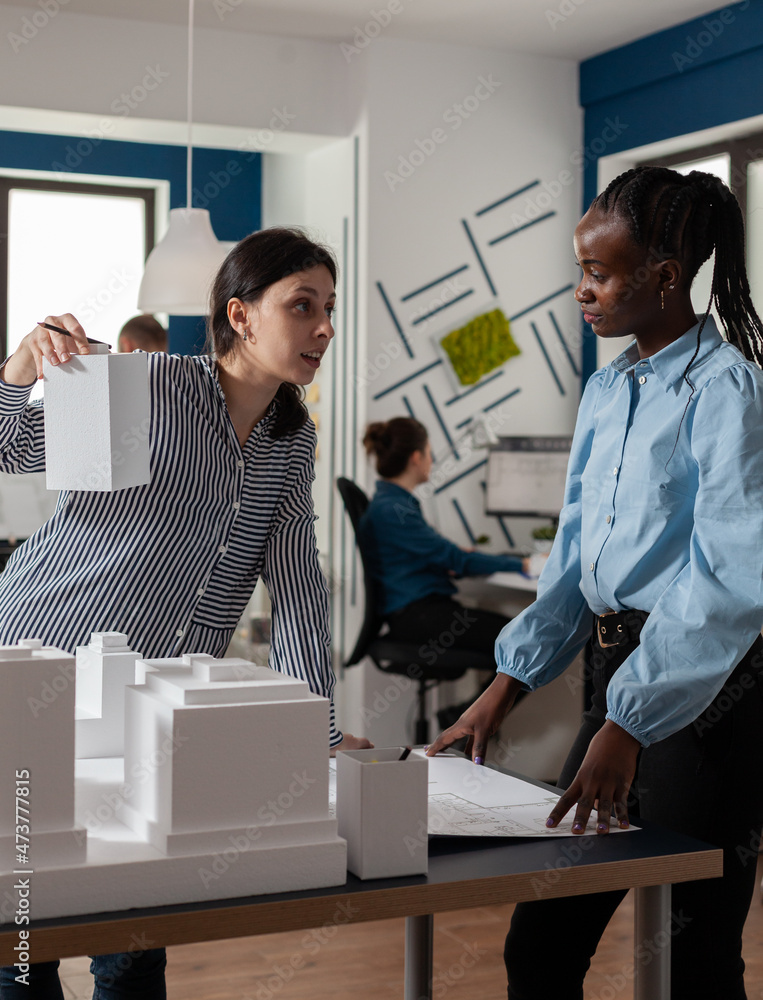 Setting Up Model Building Workplace Architect presenting foam scale building model to engineer coworker ...