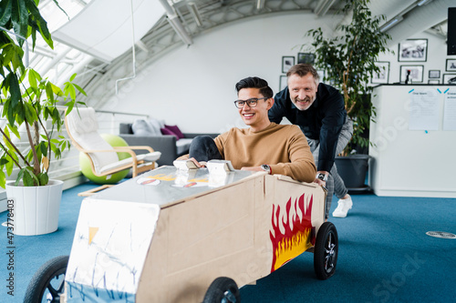 Smiling colleagues playing with toy car at office