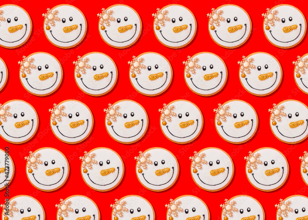 Pattern of snowman shaped Christmas cookies flat laid against vibrant red background Pattern of snowman shaped Christmas cookies flat laid against vibrant red background