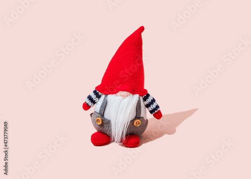 Studio shot of small dwarf figurine standing against pink background