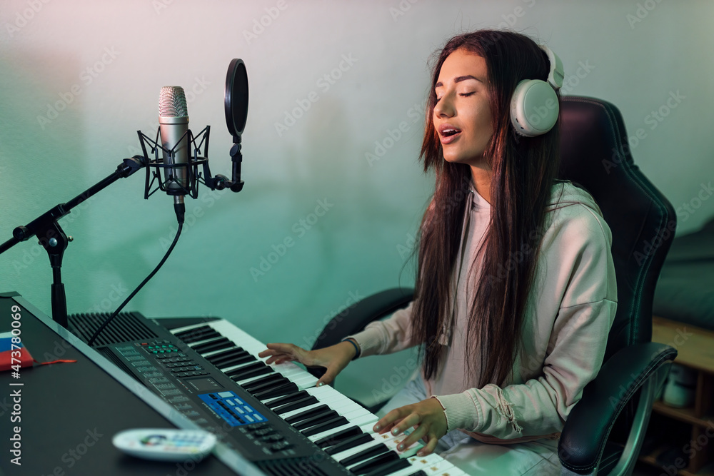 Young female singer singing while playing piano in studio Young female singer singing while playing piano in studio
