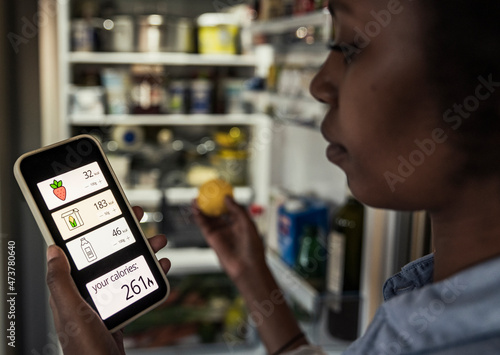 Woman counting calories through smart phone app at home photo