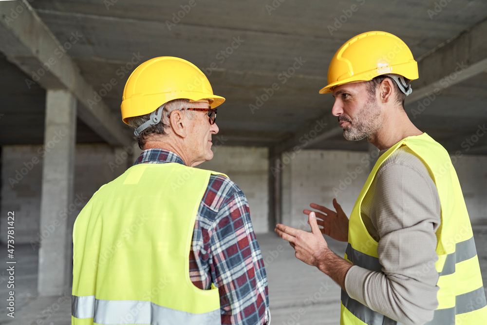 Back view of two caucasian engineers discussing on construction site Back view of two caucasian engineers discussing on construction site
