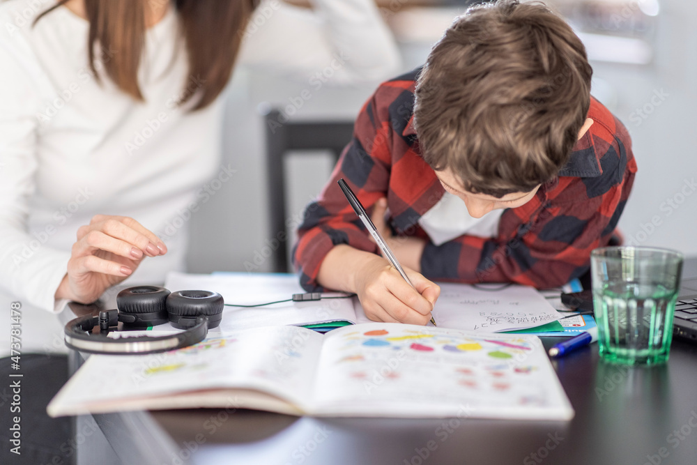 Boy doing homework by mother at home Boy doing homework by mother at home