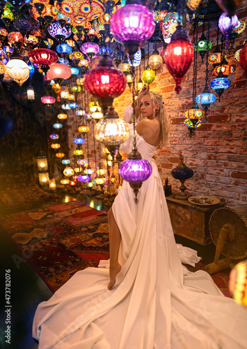 Beautiful blonde woman in long white dress posing with Turkish traditional lanterns at Istanbul Grand Bazar