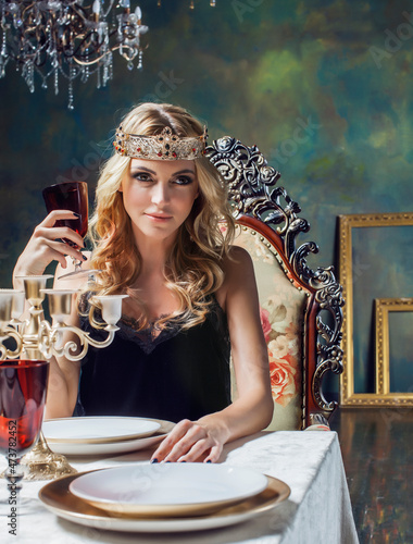 young blond woman wearing crown in fairy luxury interior with empty antique frames total wealth concept