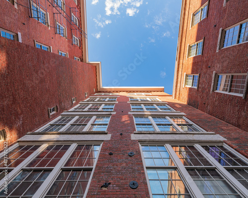 Looking skyward in an old mill factory that is a historic park and has been restored New England mill restored and now also living space, old windows symmetrical brick walls with star bolts 