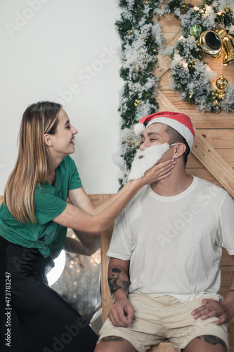 Portrait of lovely couple. New Year's photo of happy couple. Laughing and having fun together. Man in red Christmas hat and fake beard
