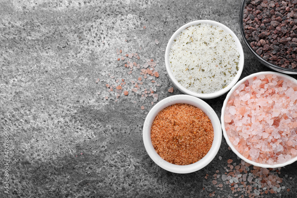 Different kinds of salt on grey table, flat lay. Space for text Different kinds of salt on grey table, flat lay. Space for text