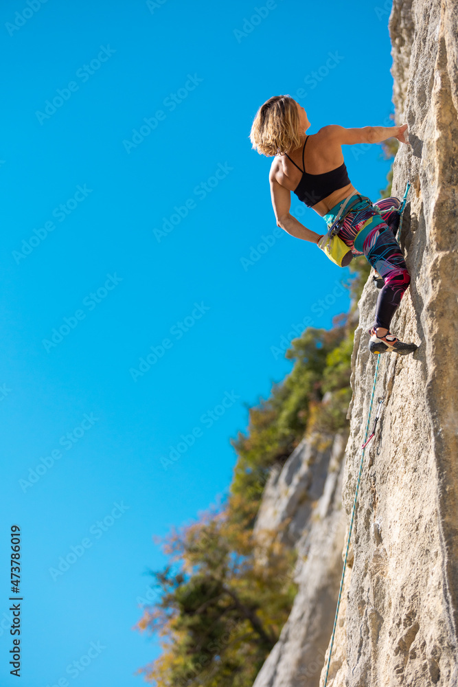 Fototapeta premium The girl climbs the rock.