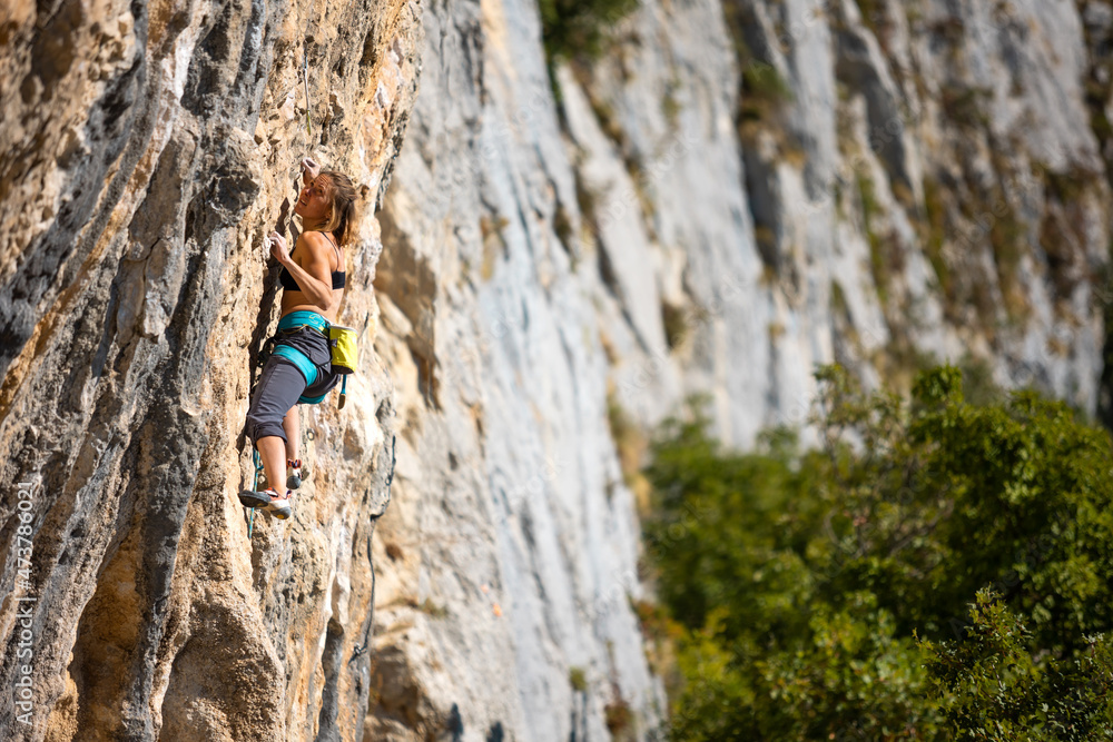A strong girl climbs a rock