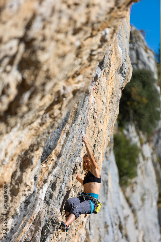 Fototapeta premium A strong girl climbs a rock