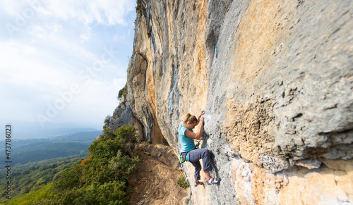 A strong girl climbs a rock