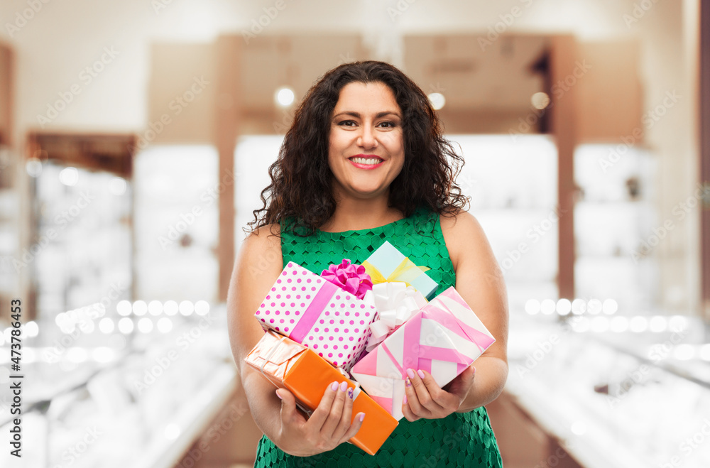 holidays, shopping and sale concept - happy woman in green dress holding gift boxes over jewelry store background holidays, shopping and sale concept - happy woman in green dress holding gift boxes over jewelry store background