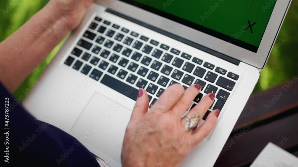 Top view of the elderly hands of a woman working at a computer and looking at a green screen. Outdoors Top view of the elderly hands of a woman working at a computer and looking at a green screen. Outdoors