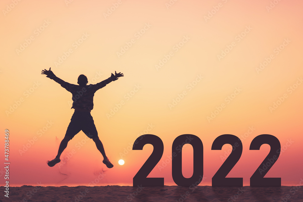 Silhouette man jumping with number like 2022 at tropical beach on sunset sky abstract background. Happy new year and holiday celebration concept. Silhouette man jumping with number like 2022 at tropical beach on sunset sky abstract background. Happy new year and holiday celebration concept.