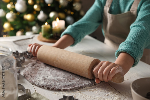 Little child rolling dough for Christmas cookies at white wooden table indoors, closeup